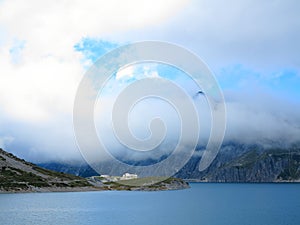 Dammed mountain lake high alpine landscape in clouds photo