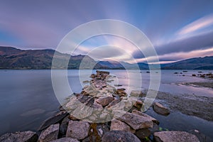 Clouds movements over a stones jetty at dawn at Lake Wanaka in New Zealand