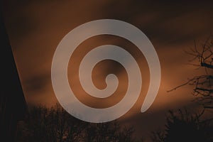 Clouds moving quickly over a dramatic night sky behind trees