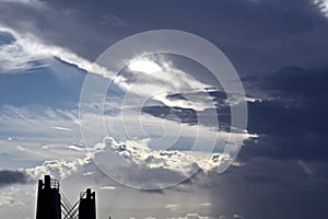 The clouds are multicolored, thunderous bizarre shapes against the blue sky and the sun above the ocean surface.