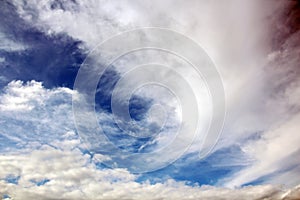 The clouds are multicolored, thunderous bizarre shapes against the blue sky and the sun above the ocean surface.