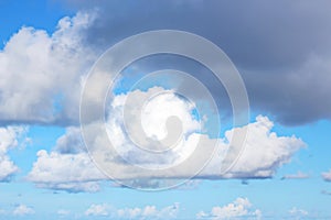 The clouds are multicolored, thunderous bizarre shapes against the blue sky and the sun above the ocean surface.