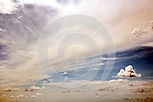 The clouds are multicolored, thunderous bizarre shapes against the blue sky and the sun above the ocean surface.