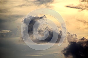 The clouds are multicolored, thunderous bizarre shapes against the blue sky and the sun above the ocean surface.