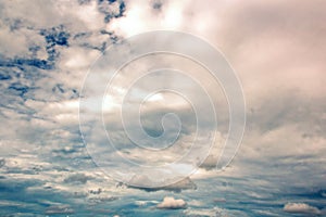 The clouds are multicolored, thunderous bizarre shapes against the blue sky and the sun above the ocean surface.