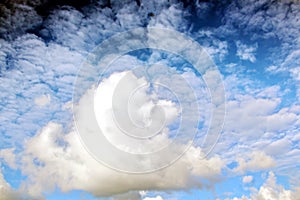 The clouds are multicolored, thunderous bizarre shapes against the blue sky and the sun above the ocean surface.