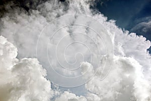 The clouds are multicolored, thunderous bizarre shapes against the blue sky and the sun above the ocean surface.