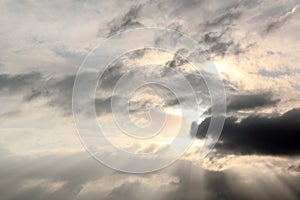 The clouds are multicolored, thunderous bizarre shapes against the blue sky and the sun above the ocean surface.