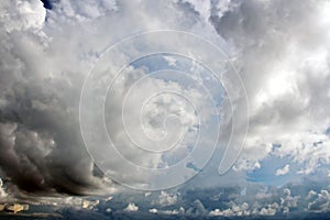 The clouds are multicolored, thunderous bizarre shapes against the blue sky and the sun above the ocean surface.