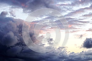 The clouds are multicolored, thunderous bizarre shapes against the blue sky and the sun above the ocean surface.