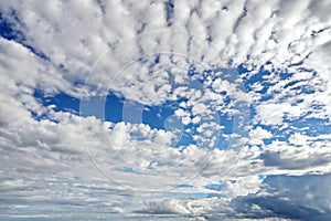 The clouds are multicolored, thunderous bizarre shapes against the blue sky and the sun above the ocean surface.