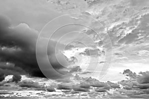 The clouds are multicolored, thunderous bizarre shapes against the blue sky and the sun above the ocean surface.