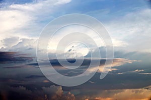 The clouds are multicolored, thunderous bizarre shapes against the blue sky and the sun above the ocean surface.