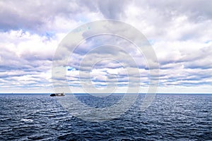 The clouds are multicolored, thunderous bizarre shapes against the blue sky and the sun above the ocean surface. Seascapes.