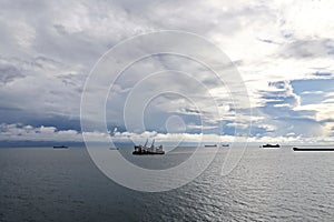 The clouds are multicolored, thunderous bizarre shapes against the blue sky and the sun above the ocean surface. Seascapes.