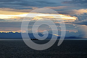 The clouds are multicolored, thunderous bizarre shapes against the blue sky and the sun above the ocean surface. Seascapes.