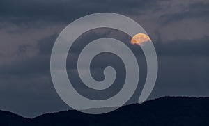 Full moon rising behind clouds