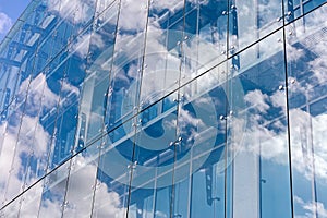 Clouds reflected on glass facade wall of modern office building