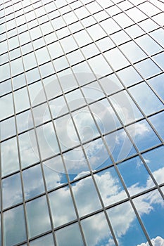 Clouds reflected in windows of modern office building. Facade texture of a glass mirrored office building