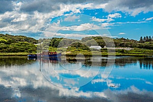 Clouds reflecting in the water, a ship anchored in the water at high tide in Clifden Bay