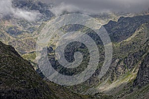 Clouds rise on the valley and surround the slopes and rocks