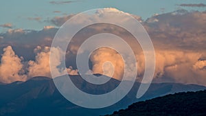 Clouds rising above the mountain ridge in the sunset, forecasting a storm