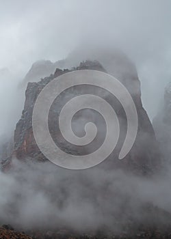 Clouds shroud a high red sandstone peak in Zion National park Utah