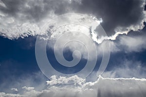 Clouds with silver lining - dark cloud lined with white in dark blue sky with tumultous clouds surrounding