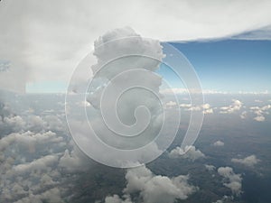 Clouds and sky as seen through window of an aircraft. The wing of airplane and sunset on blue sky and beautiful clouds.Light sun t