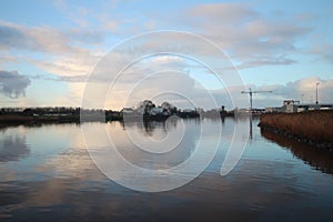 clouds and sunrise mirrors on the river Hollandse IJssel in the