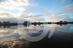 clouds and sunrise mirrors on the river Hollandse IJssel in the