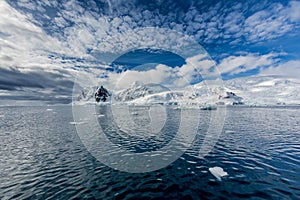 Clouds surround Antarctic peninsula mountains covered in fresh snow