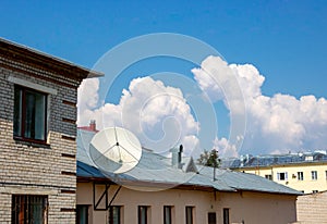 Clouds and a TV antenna. white satellite dish on the roof.