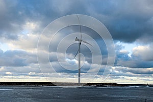 Cloudy blue sky with large wind mill and open water