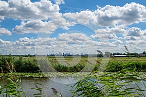Cloudy blue sky and skyline of Rotterdam city seen from the polder.