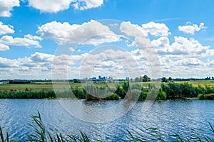 Cloudy blue sky and skyline of Rotterdam city seen from the polder.