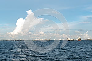 Cloudy blue sky and wavy sea met in the horizon. Ships sailing in the ocean.