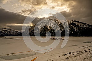 Cloudy colorful skies and winter sunset over mountain peaks at Lake Minnewanka