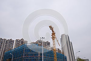 On a cloudy day, the tower crane on the construction site is working