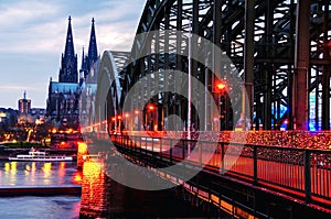 Cloudy day view of Cathedral and illuminated Hohenzollern bridge in Cologne, Germany