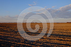 Cloudy evening sky over an empty agricultural field. Bright sunset landscape