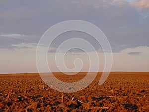 Cloudy evening sky over an empty agricultural field. Bright sunset landscape