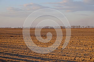 Cloudy evening sky over an empty agricultural field. Bright sunset landscape