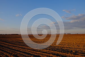 Cloudy evening sky over an empty agricultural field. Bright sunset landscape