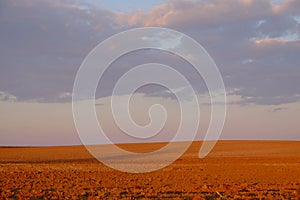 Cloudy evening sky over an empty agricultural field. Bright sunset landscape