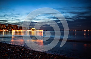 cloudy evening view of the bright lights of the building and the city center of the resort of Gelendzhik from the beach