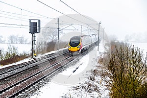 Cloudy foggy winter day view of Train on UK Railroad in England. Emma storm railway landscape.