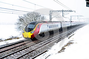 Cloudy foggy winter day view of Train on UK Railroad in England. Emma storm railway landscape.