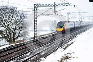 Cloudy foggy winter day view of Train on UK Railroad in England. Emma storm railway landscape.