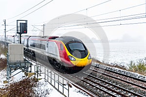 Cloudy foggy winter day view of Train on UK Railroad in England. Emma storm railway landscape.